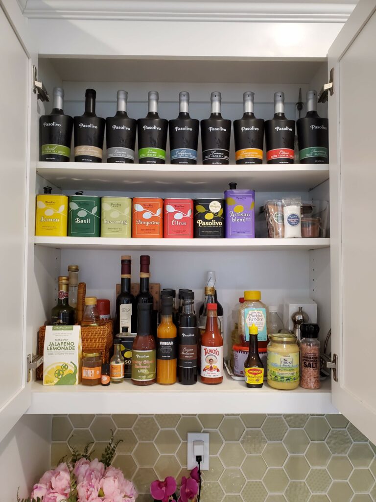 kitchen pantry shelf and cabinets with olive oil display flavor variety spices hot sauces tea Bella Organizing Professional home organizers and residential packing and moving management company serving the San Francisco Bay Area.