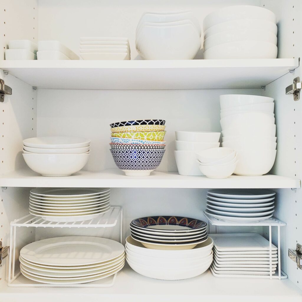 Kitchen organizational design white shelf risers plate and bowl storage cabinet Bella Organizing Professional home organizers and residential packing and moving management company serving the San Francisco Bay Area.