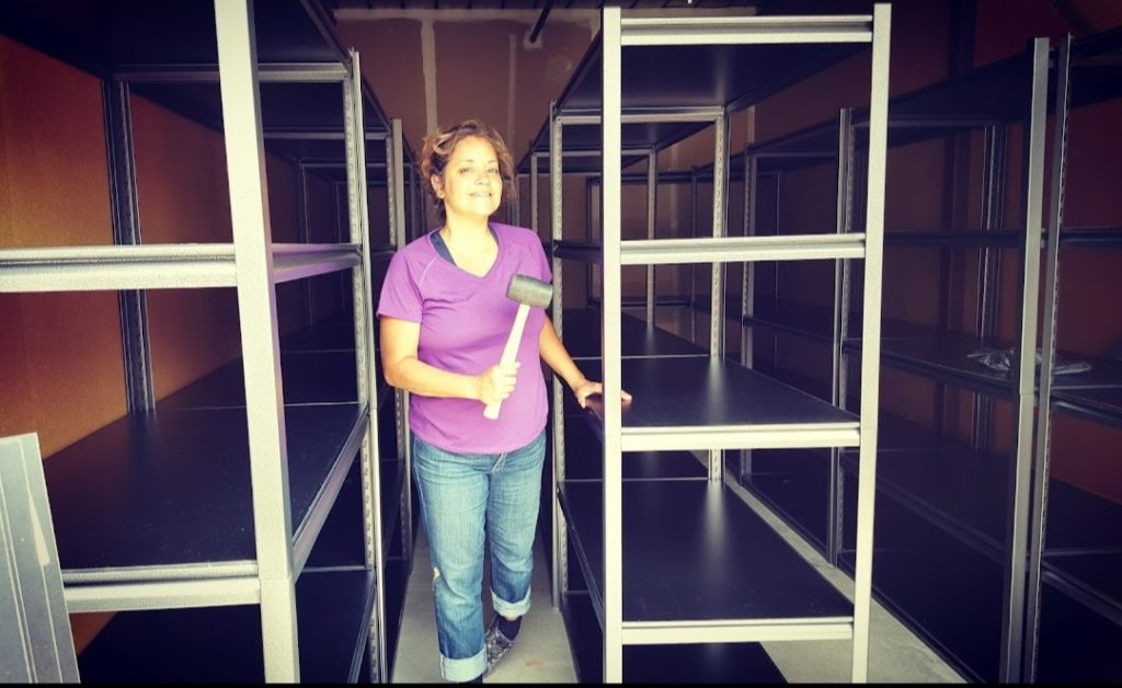 metal shelves for garage and storage unit storage build by woman in purple shirt and blue jeans with mallet Bella Organizing Professional Home Organizers in Oakland and the San Francisco Bay Area