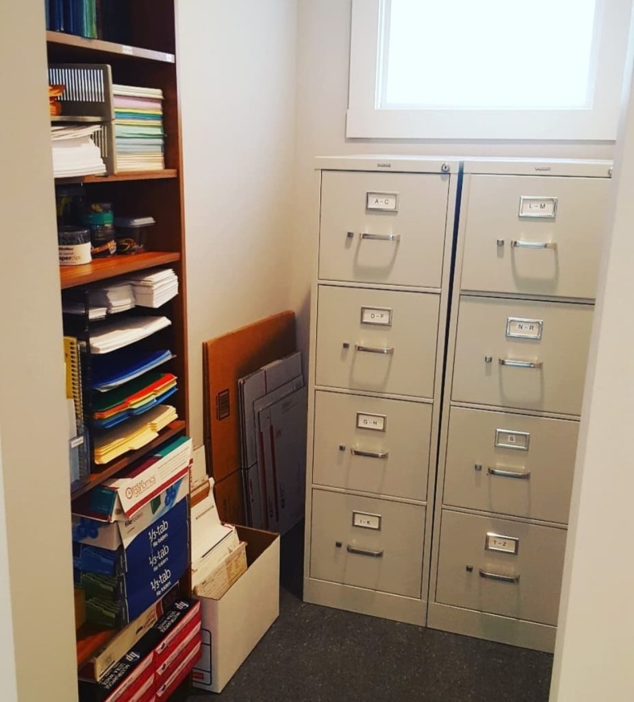 Office white metal file cabinets and paper office supplies on brown wood shelf Bella Organizing Professional home organizers and residential packing and moving management company serving the San Francisco Bay Area.